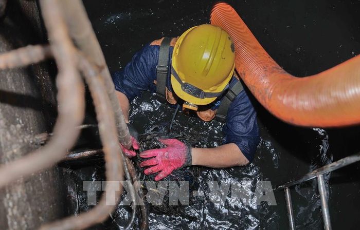 Trực tiếp ngâm mình dưới dòng nước cống đen ngòm để khơi thông dòng chảy, đảm bảo cuộc sống bình yên cho người dân Thủ đô. Ảnh: Phan Phương – TTXVN