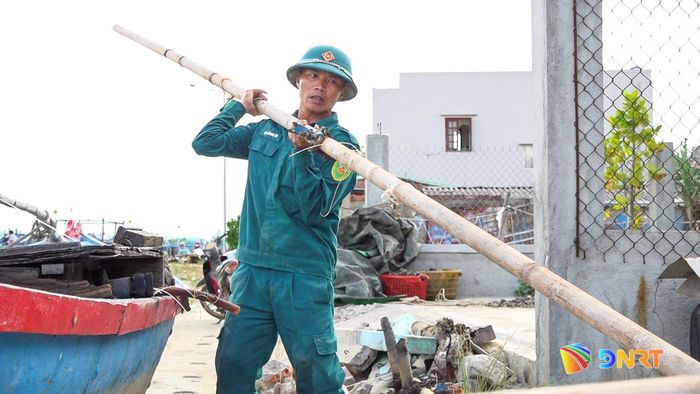 Lực lượng dân quân Núi Thành hỗ trợ người dân di dời các phương tiện, vật tư vào bờ. Ảnh: HOÀNG ĐẠO