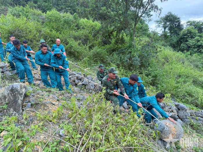 Bộ đội, dân quân di chuyển quả bom đến khu vực hủy nổ tại bản Trường Sơn, xã Nậm Cắn.
