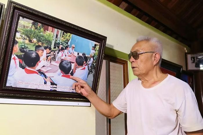 Cựu chiến binh Nguyễn Đăng Khoa bên bức ảnh lưu niệm chụp cùng học trò.