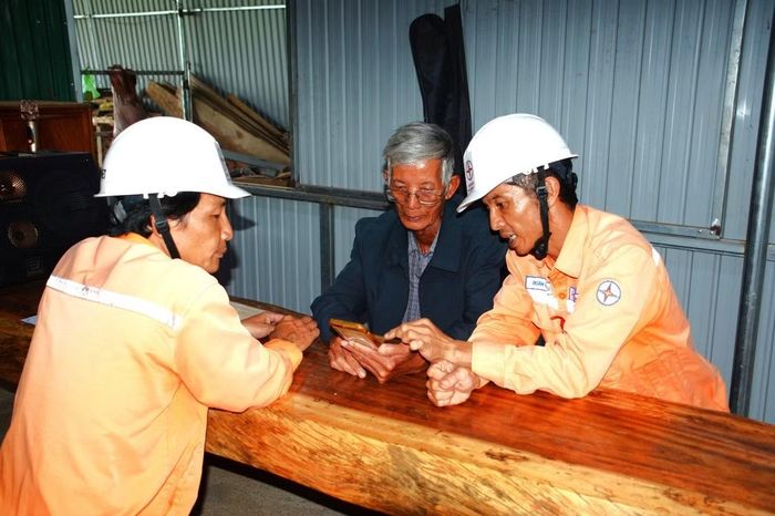 Nhân viên Điện lực Cư Jut hướng dẫn ông Lê Văn Lộc (giữa) sử dụng dịch vụ điện thông qua các kênh giao dịch trực tuyến. (Ảnh: Đại Dương)