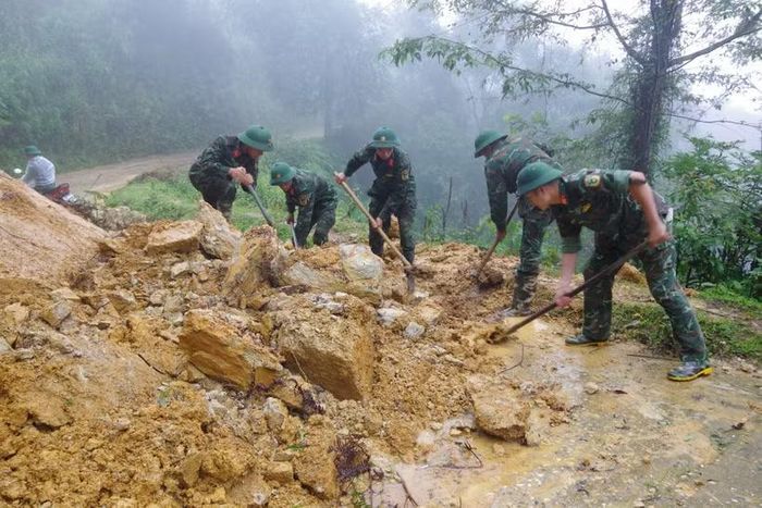 Cán bộ, chiến sỹ dọn dẹp đất đá, cây cối đổ gãy, khôi phục các tuyến giao thông tại xã Mù Cang Chải. (Ảnh: TTXVN phát)