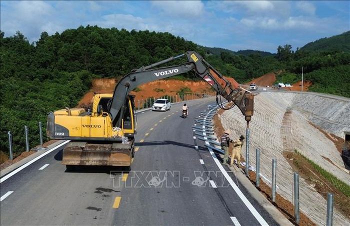 Triển khai thi công những hạng mục cuối cùng trên tuyến như lắp đặt tôn sóng hai bên đường, sơn kẻ làn đường và lắp đặt hệ thống chiếu sáng. Ảnh: Quốc khánh/TTXVN