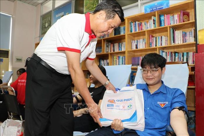 Đại diện Ban tổ chức Hành trình Đỏ Trung ương tặng quà người tham gia hiến máu. Ảnh: Hồng Thái/TTXVN