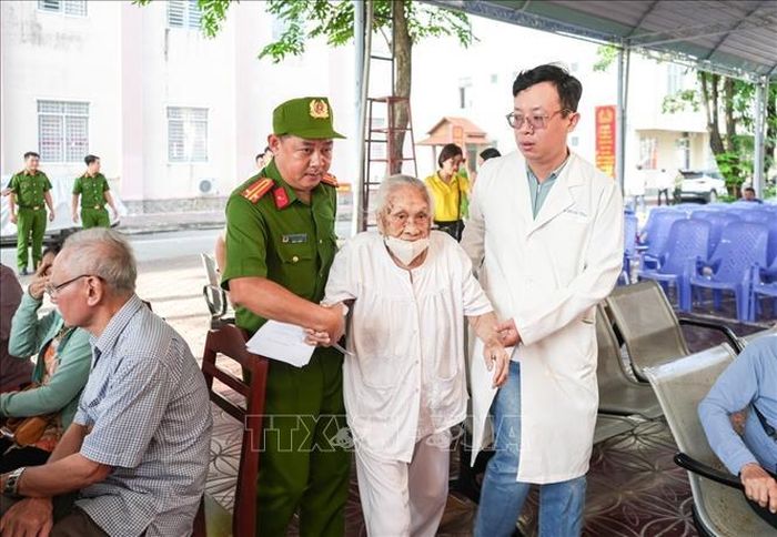 Các thân nhân liệt sĩ tuổi cao, sức yếu được cán bộ, chiến sĩ Công an thành phố tận tình hỗ trợ đưa đón. Ảnh: TTXVN phát