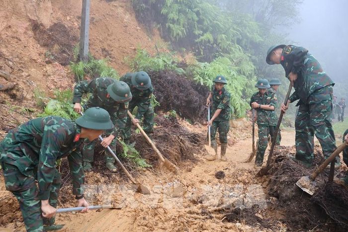 Cán bộ, chiến sĩ dọn dẹp đất đá, cây cối đổ gãy, khôi phục các tuyến giao thông tại xã Mù Cang Chải. Ảnh: TTXVN phát