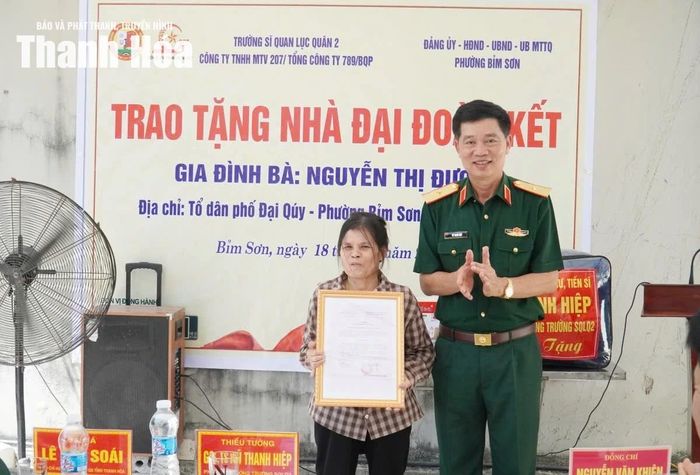 Phó Hiệu trưởng Trường Sĩ quan Lục quân 2 Vũ Thanh Hiệp trao biểu trưng xây dựng nhà tình nghĩa cho bà Nguyễn thị Đượm.