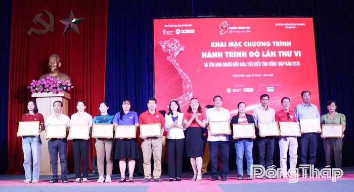 Đồng chí Lưu Thị Thanh Loan, Phó Trưởng Ban Tuyên giáo và Dân vận Tỉnh ủy Đồng Tháp (thứ 7 từ trái sang) và Chủ tịch Hội Chữ thập đỏ tỉnh Đồng Tháp, Phó Trưởng Ban Thường trực Ban Chỉ đạo vận động hiến máu tình nguyện tỉnh Đồng Tháp Đặng Thị Thu Uyên tặng Bằng khen cho đại điện hộ gia đình.