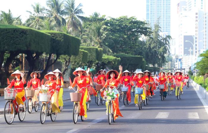 Các chị em trong tà áo dài cờ đỏ sao vàng diễu hành bằng xe đạp trên phố.