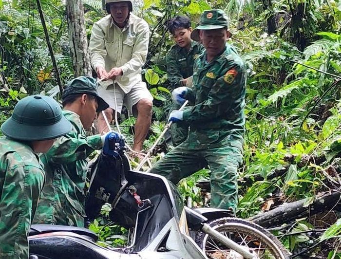 Cán bộ, chiến sĩ Đồn Biên phòng Pa Vệ Sử phối hợp đưa xe máy của công nhân gặp nạn lên khỏi khu vực ta luy sâu.