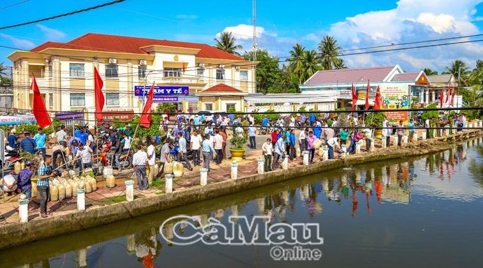 Đông đảo người dân đến theo dõi, hưởng ứng hoạt động thả cá giống trên tuyến sông trước Trạm Y tế xã Khánh Bình.