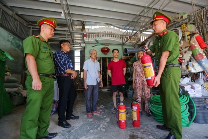 Công an xã Nam Phù tuyên truyền phòng cháy, chữa cháy cho các hộ kinh doanh trên địa bàn. Ảnh: Khánh Huy