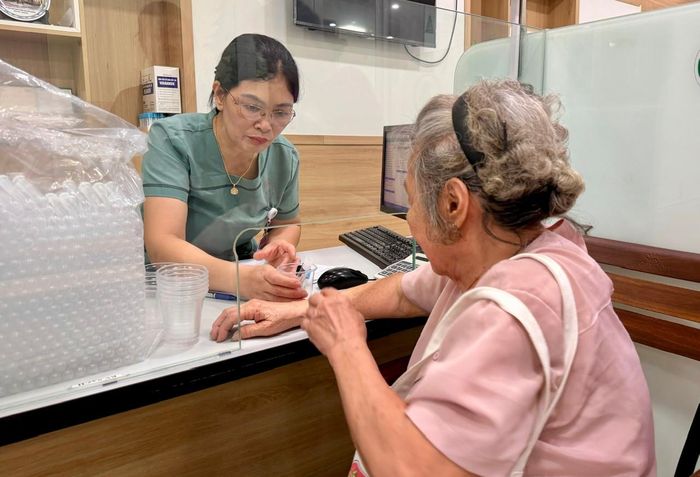 Bà Nghiêm Thị Hiếu được nhân viên y tế lấy mẫu máu xét nghiệm. Ảnh: Võ Giang