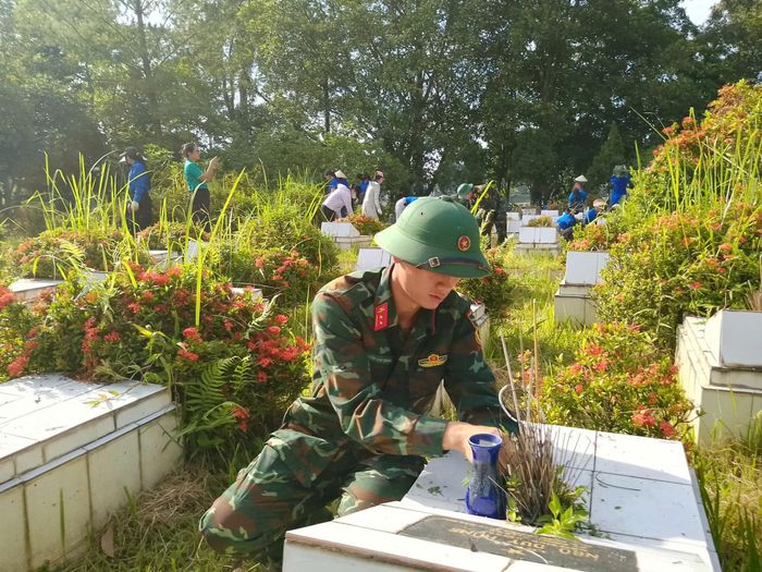 Các lực lượng tham gia vệ sinh, chăm sóc từng phần mộ, chỉnh trang khuôn viên nghĩa trang liệt sĩ. Ảnh: M.H