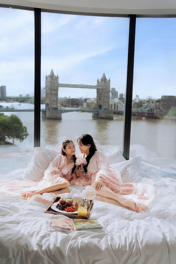 Trong ảnh, Hà Kiều Anh và con gái út - bé Vivian, cùng áo choàng ngủ màu hồng phấn, có chi tiết lông vũ mềm mại. Tông màu đồng điệu giúp mẹ con thêm phần nổi bật giữa căn phòng được phủ bởi sắc trắng và ánh nắng ban mai.