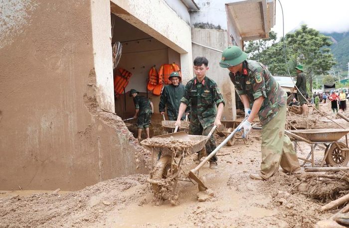 Lực lượng Quân đội giúp dân dọn bùn đất, đá trôi vào nhà tại xã Mường Than. Ảnh: Quý Trung - TTXVN