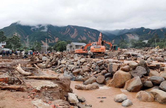 Phương tiện máy móc khơi thông, nắn dòng chảy để nhanh chóng khắc phục giao thông trên tuyến Quốc lộ 32, góp phần ổn định cuộc sống người dân sau lũ. Ảnh: Quý Trung - TTXVN