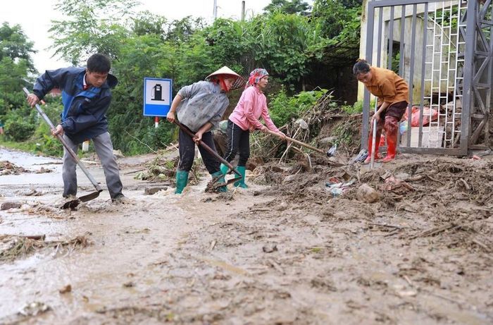 Người dân xã Mường Than tập trung dọn dẹp bùn đất sau khi cơn lũ đi qua. Ảnh: Quý Trung - TTXVN
