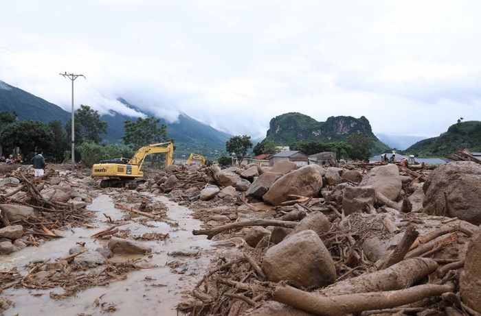 Phương tiện máy móc khơi thông, nắn dòng chảy để nhanh chóng khắc phục giao thông trên tuyến Quốc lộ 32, góp phần ổn định cuộc sống người dân sau lũ. Ảnh: Quý Trung - TTXVN