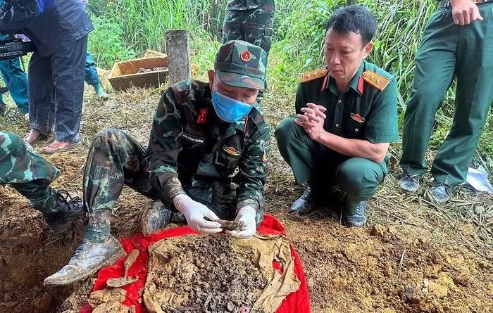 Trung tá Nguyễn Ngọc Toan (bên phải), người tự tay chôn cất hai hài cốt liệt sĩ từ năm 2005, đang chăm chú dõi theo từng di vật bên hài cốt liệt sĩ.