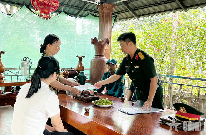 Trung tá Nguyễn Xuân Giang, Chính trị viên phó Ban CHQS xã Tân Cương (bên phải) cung cấp mẫu thông tin cho gia đình bà Đào Thị Hưởng, xóm Nam Hưng, xã Tân Cương.
