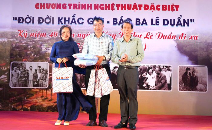 Đại diện lãnh đạo xã Triệu Phong tiếp nhận máy đo huyết áp, áo khoác do Báo SGGP trao tặng gia đình chính sách, người có công với cách mạng và học sinh vượt khó học giỏi là con em gia đình chính sách, người có công. Ảnh: VĂN THẮNG