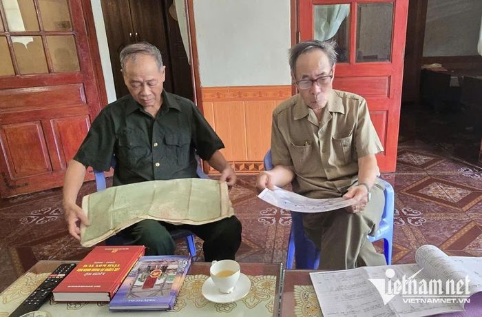 Ông Thông (bên trái) vẫn nâng niu từng tấm bản đồ, từng cuốn sổ ghi chép. Ảnh: Mỹ Dung