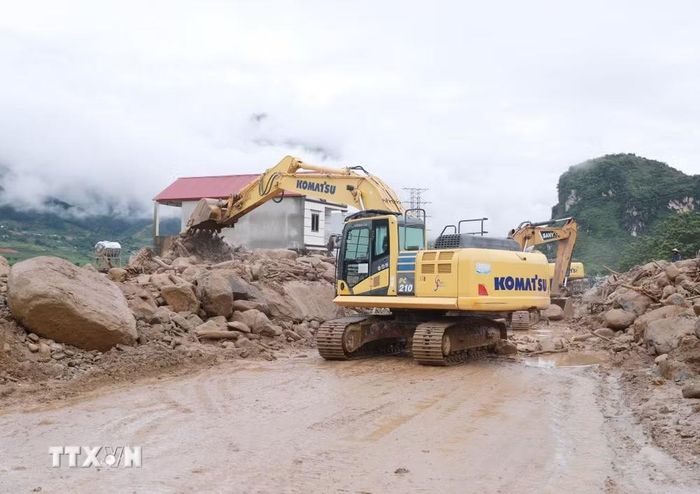 Các phương tiện máy móc tập trung san gạt cây cối, đất đá góp phần thông đường tạm thời cho nhân dân đi lại. (Ảnh: Quý Trung/TTXVN)