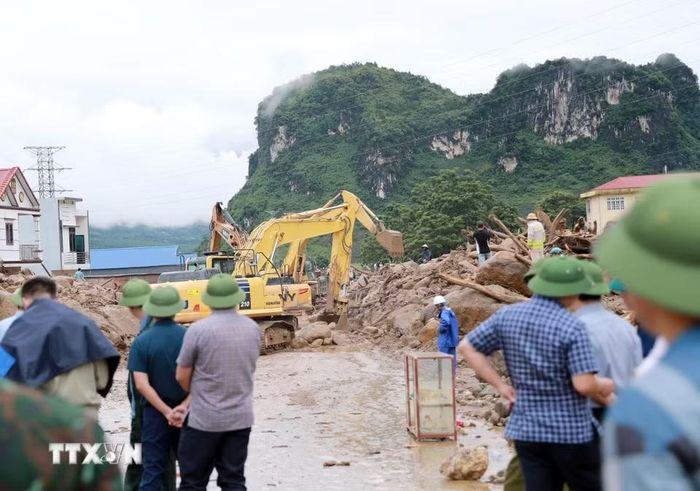 Các phương tiện máy móc tập trung san gạt cây cối, đất đá góp phần thông đường tạm thời cho nhân dân đi lại. (Ảnh: Quý Trung/TTXVN)