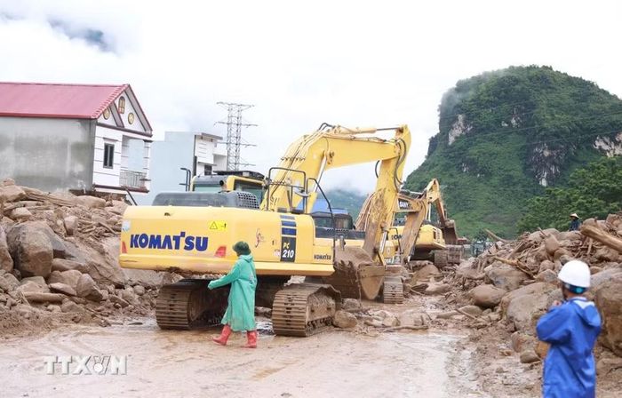 Các phương tiện máy móc tập trung san gạt cây cối, đất đá góp phần thông đường tạm thời cho nhân dân đi lại. (Ảnh: Quý Trung/TTXVN)