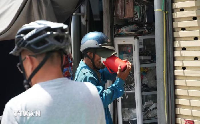 Tiếp nước cho cơ thể khi làm việc ngoài trời nắng nóng gay gắt ở chợ Đông Ba, phường Phú Xuân, thành phố Huế. (Ảnh: Nguyên Lý/TTXVN)