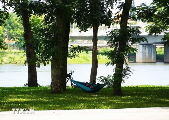 Người dân mắc võng ở công viên bờ Bắc sông Hương, thành phố Huế để nằm hóng mát, tránh nắng nóng gay gắt. (Ảnh: Nguyên Lý/TTXVN)