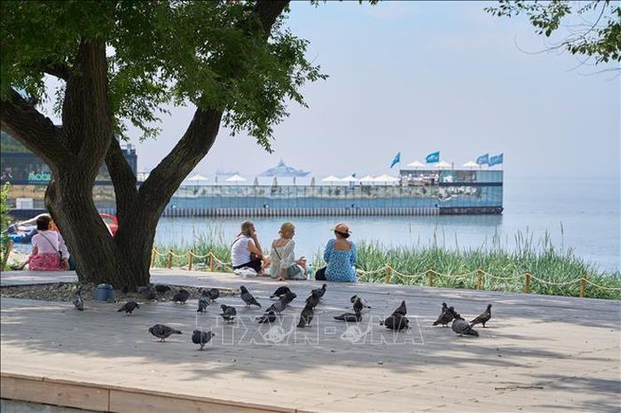 Khách du lịch ngồi nghỉ dưới bóng râm tại Vladivostok, Nga. Ảnh minh họa: THX/TTXVN