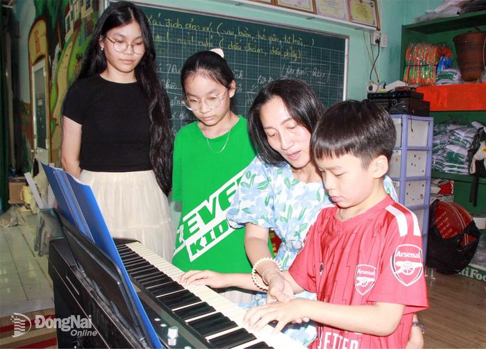 Bà Nguyễn Thị Phương Anh hướng dẫn con trai làm quen với đàn. Ảnh: Nga Sơn