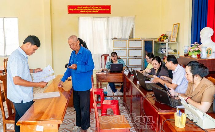 Trưởng Khóm 20 Huỳnh Quốc Tiếng (bìa trái) hỗ trợ người dân tra cứu thông tin liên quan đến các thủ tục hành chính.