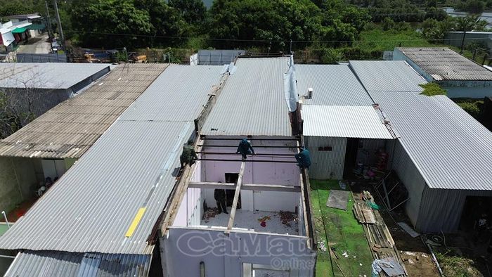 Lực lượng xã Định Thành khẩn trương hỗ trợ người dân tháo dỡ mái nhà, di dời tài sản ra khỏi khu vực sạt lở nguy hiểm.