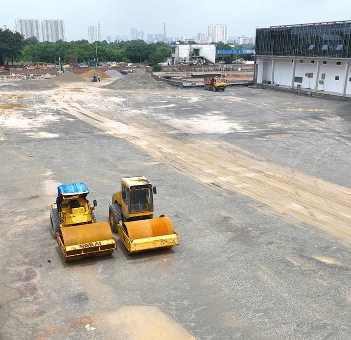 Bên ngoài khu nhà chính, các đơn vị thi công đang triển khai san nền, thảm nhựa, đổ bê tông tuyến đường nội bộ, hoàn thiện bãi đỗ xe, vỉa hè và trồng cây xanh.