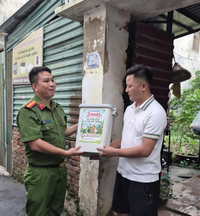 Thiếu tá Ngô Minh Ngọc trao tặng thùng rác cho một hộ dân tại ngõ 28. Ảnh: Tuệ Lâm