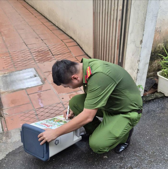 Thiếu tá Ngô Minh Ngọc, Cảnh sát khu vực Công an phường Phú Thượng, ghi địa chỉ từng hộ trong ngõ 28 lên thùng rác trước khi bàn giao cho người dân sử dụng. Ảnh: Tuệ Lâm