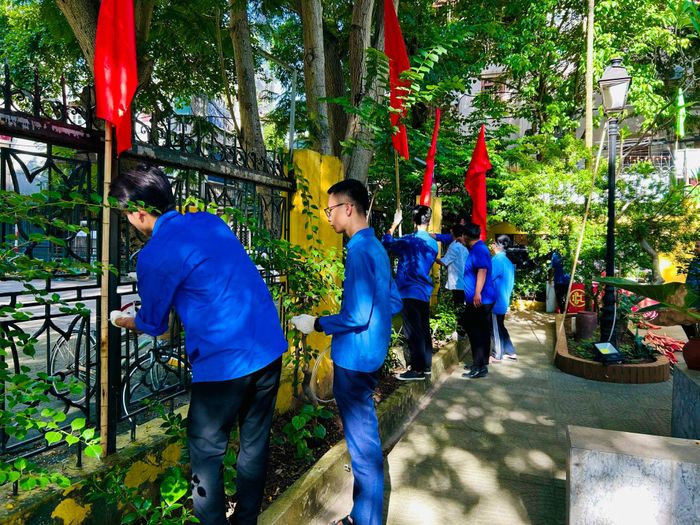 Các đoàn viên thay cờ mới tại Nhà bia tưởng niệm các anh hùng liệt sĩ phường Giáp Bát cũ. Ảnh: Trần Oanh.