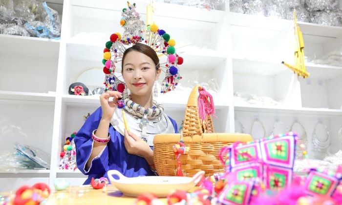 Một phụ nữ trẻ trưng bày một chiếc túi thơm truyền thống, nằm trong danh sách di sản văn hóa phi vật thể cấp huyện, tại một cửa hàng quần áo ở thị trấn Guyi, Khu tự trị dân tộc Choang Quảng Tây, miền Nam Trung Quốc, ngày 18/6. Ảnh: VCG.