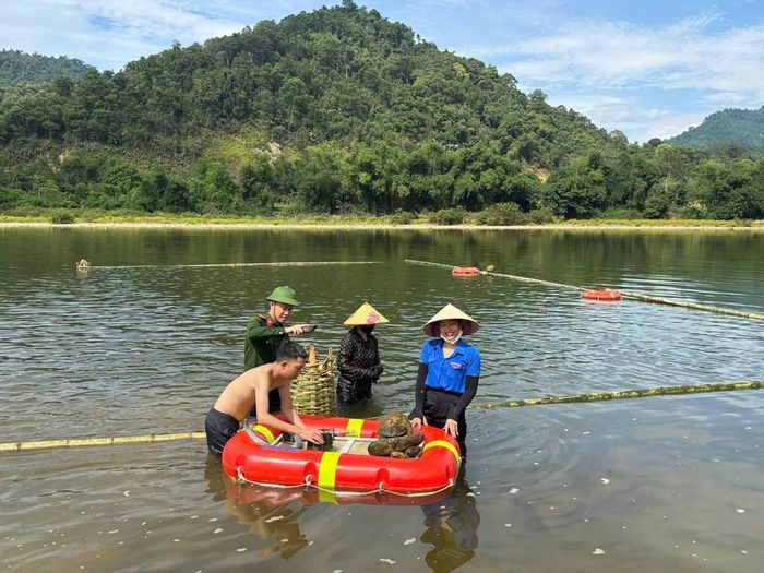 Các đoàn viên thanh niên và chiến sĩ công an bỏ đá vào rọ rồi quây thành bể bơi trên sông