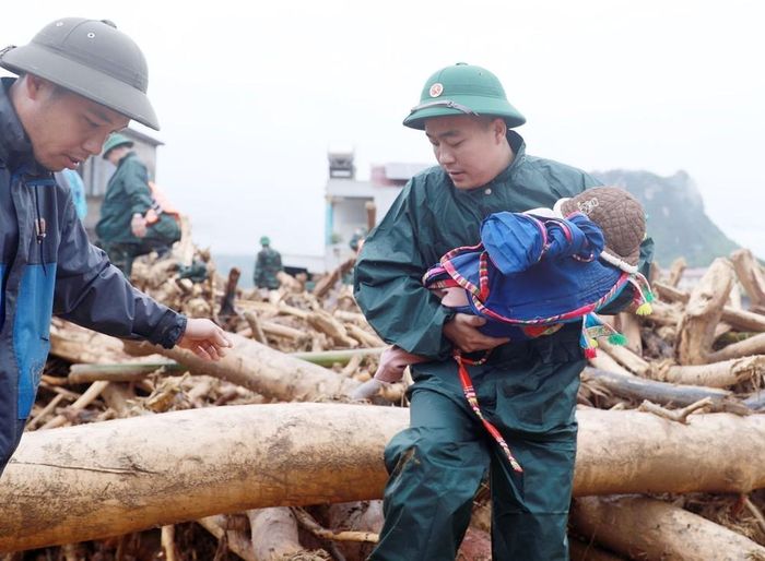 Lực lượng dân quân tựu vệ đưa trẻ em ra khỏi nơi nguy hiểm tại khu vực xảy ra lũ quét xã Mường Than, tỉnh Lai Châu. Ảnh: Quý Trung – TTXVN