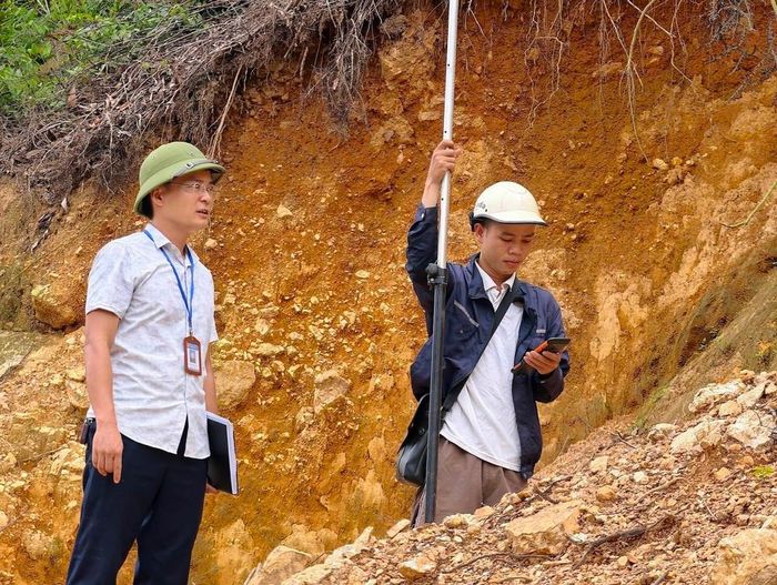 Cán bộ UBND xã Sóc Sơn và đơn vị chuyên môn khảo sát, đo đạc hiện trạng mái dốc để phục vụ việc lập phương án xử lý sự cố sạt trượt. Ảnh: Quốc Lũy - TTXVN