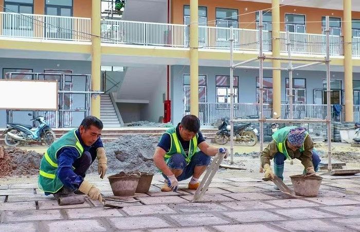 Tỉ mẩn lát gạch sân trường.