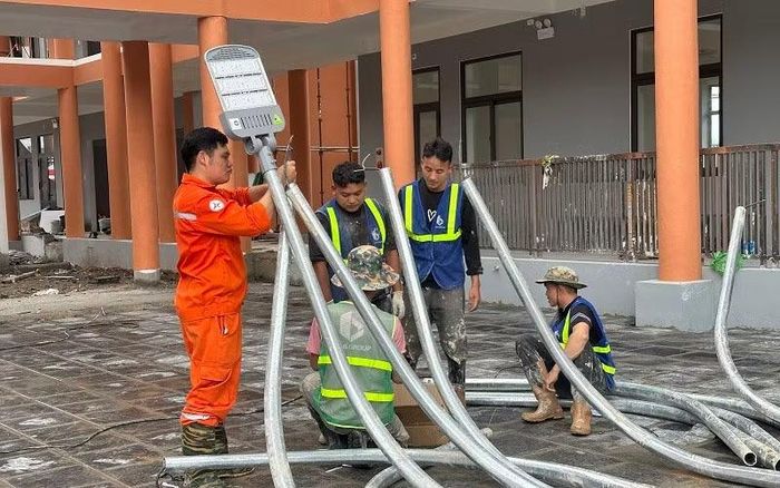 Công nhân khẩn trương lắp đặt hệ thống điện chiếu sáng quanh sân trường nội trú liên cấp Thanh Nưa.