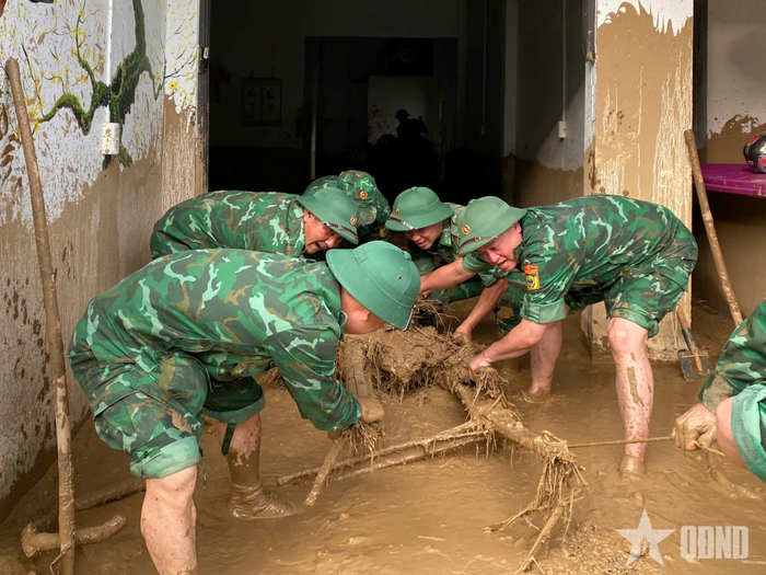 Cán bộ, chiến sĩ Bộ đội Biên phòng tỉnh Lai Châu kéo thân cây lớn bị mắc kẹt trong một căn nhà ở bản Nậm Sáng, xã Mường Than.