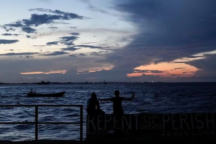 Người dân ngồi ngắm hoàng hôn trên biển ở Georgetown, Guyana, ngày 19/11/2024. Ảnh tư liệu: AP/Matias Delacroix.