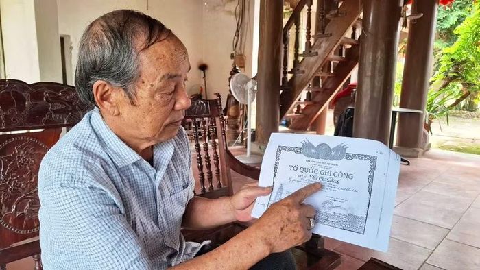 Ông Hà Chí Cẩn cầm tấm Bằng "Tổ quốc ghi công" của liệt sĩ Hà Chí Đính.