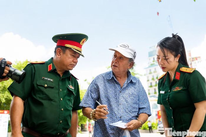 Ông La Văn Hai dùng cử chỉ và điện thoại để truyền đạt ký ức về rãnh mộ tập thể mà ông chứng kiến gần 60 năm trước. Ảnh: Nguyễn Tiến.